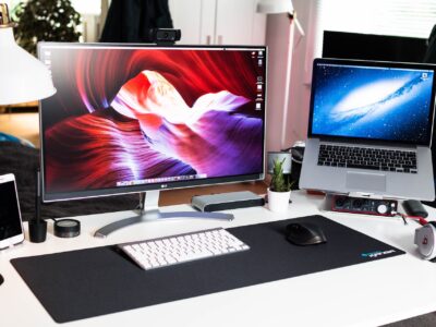 laptop, monitor, keyboard and a headphones placed in a workstation of a user.