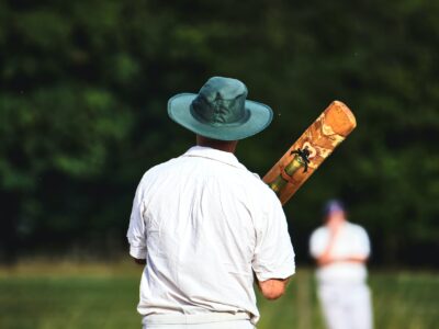 Kumar Sangakara backside holding bat while standing and wearing green cap