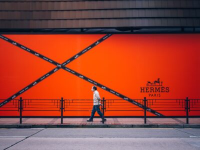 A person walking infront of the Hermes brand wall