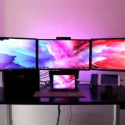 3 monitors working side by side with displays on for working near a window