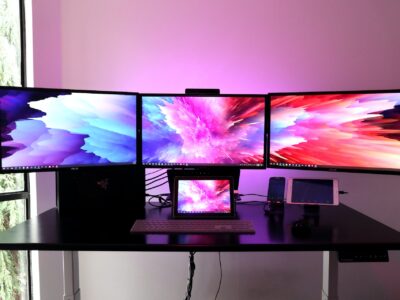 3 monitors working side by side with displays on for working near a window